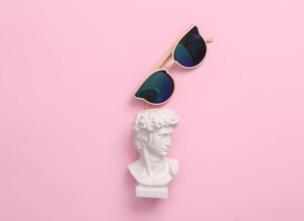 David bust met een zonnebril op een roze achtergrond. Minimale popcultuur indeling. Bovenaanzicht - Foto, afbeelding