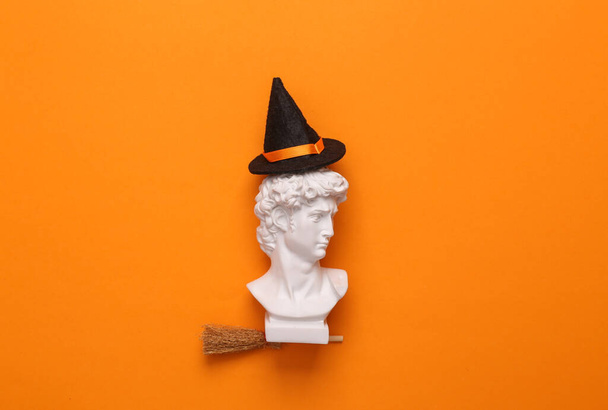 Дэвид накрыл метлу ведьмы в шляпе на оранжевом фоне. 31 октября, счастливая концепция Хэллоуина, минимальное оформление. Вид сверху - Фото, изображение