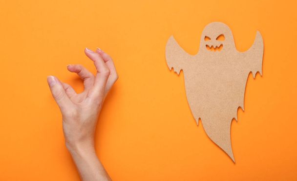 Gelukkig Halloween concept. Hand en houten geest op oranje achtergrond. Snoep of ik schiet. Bovenaanzicht  - Foto, afbeelding