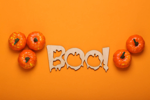 Szczęśliwego halloween koncepcji. Drewniane słowo Boo! i dynie na pomarańczowym tle. Cukierek albo psikus. Widok z góry  - Zdjęcie, obraz