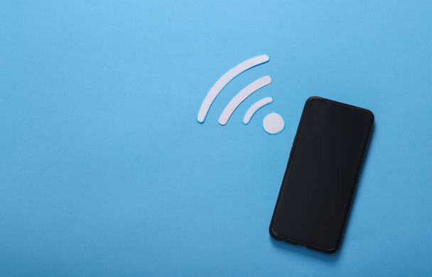 Wellen-Wi-Fi-Symbol und Smartphone auf blauem Hintergrund. - Foto, Bild