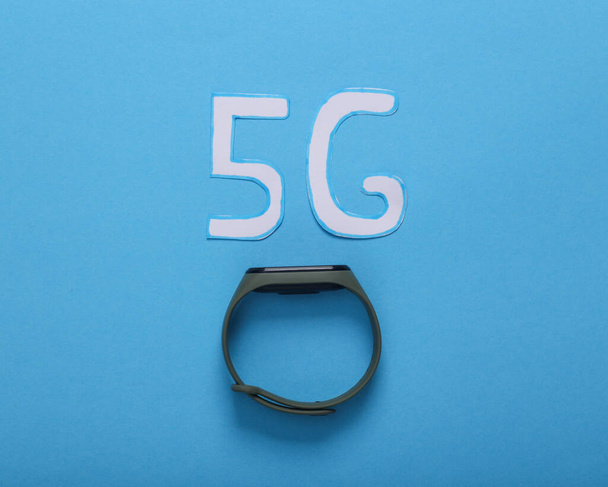 Papiergeschnittenes 5g-Symbol mit intelligentem Armband auf blauem Hintergrund. Ansicht von oben - Foto, Bild