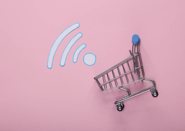 E-ticaret. Pembe arka planda alışveriş arabası olan Wi-Fi ikonu. Üst görünüm - Fotoğraf, Görsel
