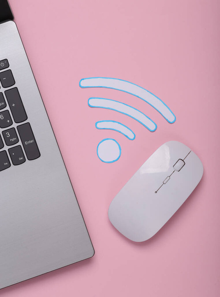Corte de papel Waves wi-fi icono y portátil, ratón PC sobre fondo rosa. Vista superior - Foto, Imagen