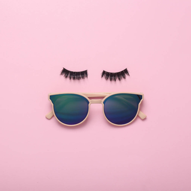 Pestañas con gafas de sol sobre fondo rosa. Diseño creativo mínimo, concepto de belleza - Foto, imagen