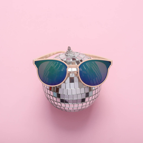 Минимальная концепция вечеринки. Солнечные очки с шаром диско на розовом фоне. Вид сверху - Фото, изображение