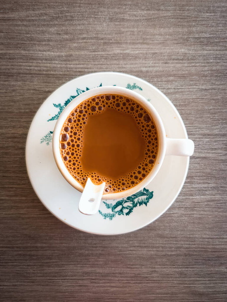 Latte asiático con espuma espumosa o café blanco, vista de ángulo alto en la mesa de madera.  - Foto, Imagen