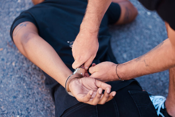 Hände, Handschellen und ein Mann auf dem Boden mit Polizisten, Justiz und Menschenrechten im Iran, um Proteste zu stoppen. Kriminalität, Recht und Freiheit bei Verhaftung auf der Straße, Verbrecher oder Dieb in der Stadt von Polizisten verhaftet. - Foto, Bild