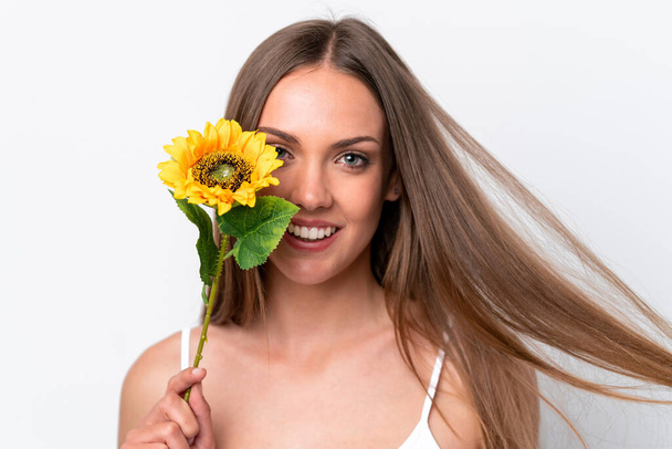 Young caucasian woman isolated on white background holding a sunflower while smiling. Close up portrait - Фото, зображення