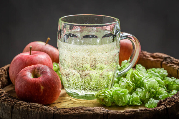 Fresh and sparkling cider beer with hops, apples and wheat on old wooden barrel - Foto, afbeelding