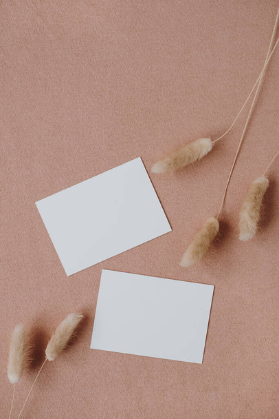 Blanco papieren uitnodigingskaarten met kopieerruimte op neutrale pastel elegante koraalachtergrond. Flat lay, bovenaanzicht esthetische minimalistische bruiloft uitnodigingen - Foto, afbeelding
