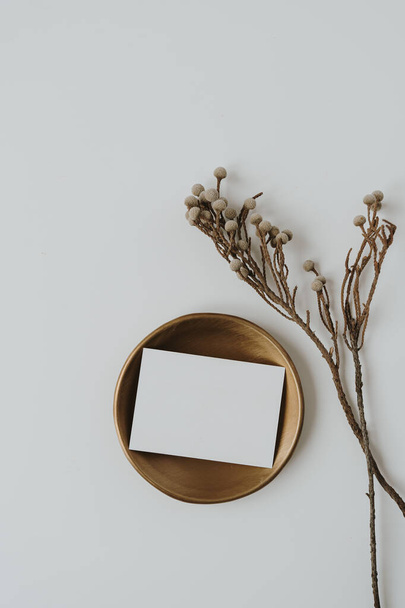 Üres papír kártya rézlemezre másolható, szárított virágos ág fehér háttérrel. Top view, flat lay minimalista esztétikai luxus bohém üzleti márka koncepció - Fotó, kép