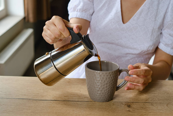 Tyttö pitelee moka potin käsissään keittää kuumaa tuoretta kahvia. Lähikuva metalli kahvipannu. Laitteet kahvin keittämiseen. Ammattimainen kahvinvalmistus - Valokuva, kuva