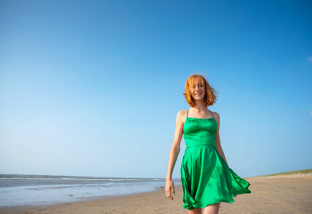 щаслива молода дівчина в зеленій сукні на пляжі
 - Фото, зображення