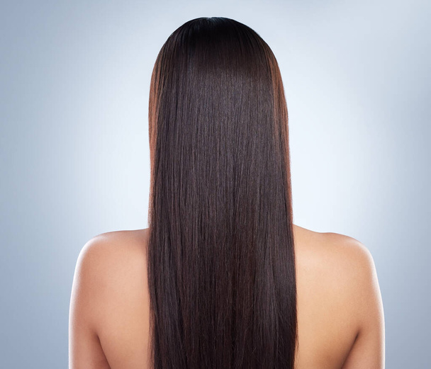 Rear view of a young woman with beautiful long smooth hair. Close up of a woman with luxurious straight and shiny brown hair. Healthy hair against studio background. - Фото, зображення