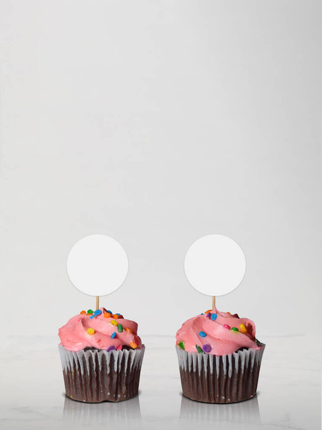 Lähikuva kaksi herkullista vaaleanpunainen himmeä suklaa cupcakes lepää tyylikäs marmori keittiö kohtaus. Runsaasti kopiotilaa.  - Valokuva, kuva