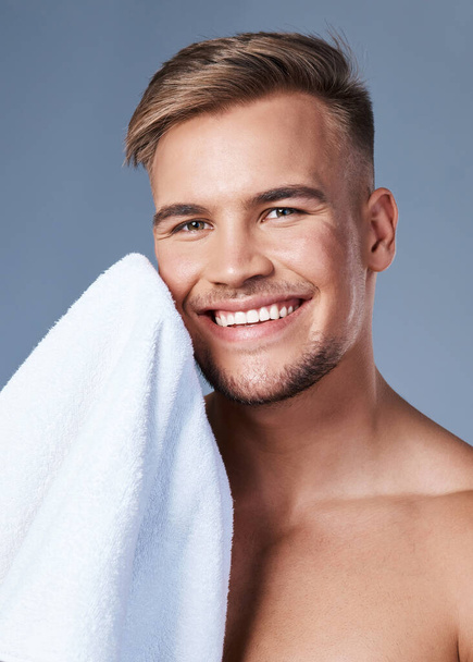 Начните свой день с кожи, которая чувствует себя здоровым. красивый молодой человек вытирает лицо полотенцем - Фото, изображение