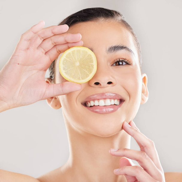 Vitamine zien. Studio portret van een jonge vrouw poseren met een halve citroen tegen een grijze achtergrond - Foto, afbeelding