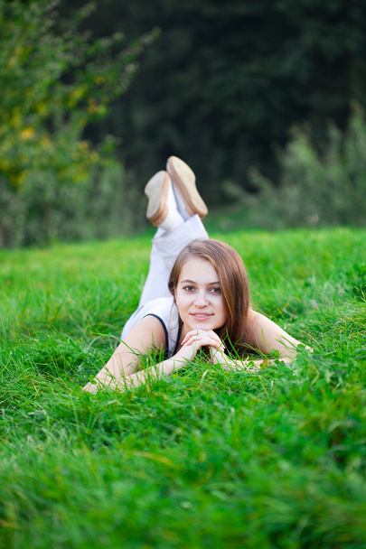 Beautiful young woman lying on green grass - Fotografie, Obrázek