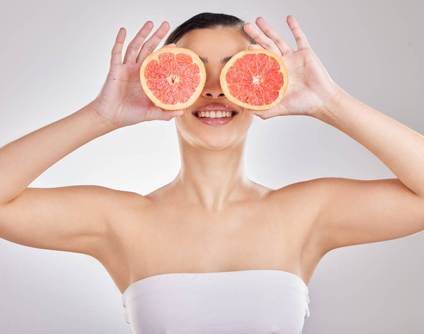 Geef je huid wat ze nodig heeft. Studio portret van een jonge vrouw poseren met een halve grapefruit tegen een grijze achtergrond - Foto, afbeelding