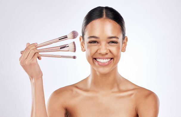Brushing my way to the top. a happy young woman holding a set of makeup brushes against a studio background - Фото, изображение