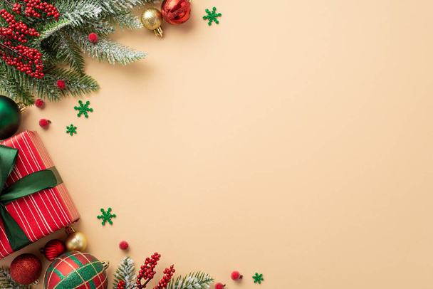 クリスマスのコンセプト。トップ表示写真の現在のボックスでリボン弓金赤と緑のボールボールミステリーベリー松の枝でharfrostとconfettiで隔離されたベージュの背景にコピースペース - 写真・画像