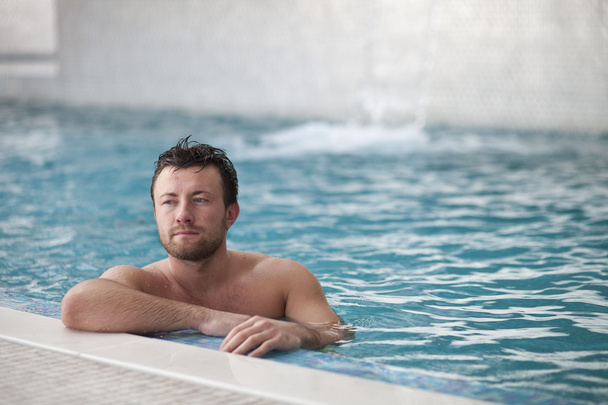 Man leaning at edge of swimming pool - 写真・画像