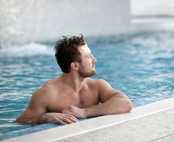 Man leaning at edge of swimming pool - Foto, afbeelding