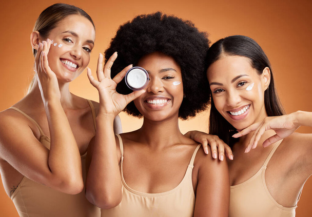Beauty, skincare and portrait of women with smile in studio with face cream or moisturizer. Happiness, diversity and friends with facial routine for cosmetics, health and wellness by brown background. - Fotografie, Obrázek