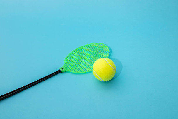 Capteur de mouches en plastique et balle de tennis sur fond bleu. - Photo, image