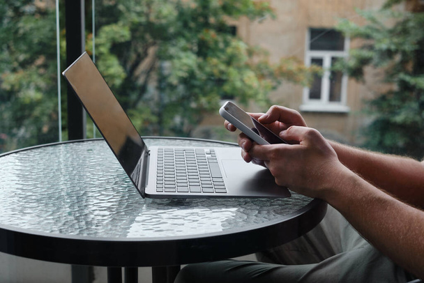 Een man werkt op een laptop en een smartphone aan tafel. Werk op afstand van huis, bedrijfsruimte. Zakenmensen aan het werk op kantoor. Zakelijke achtergrond. Binnenlandse Zaken - Foto, afbeelding