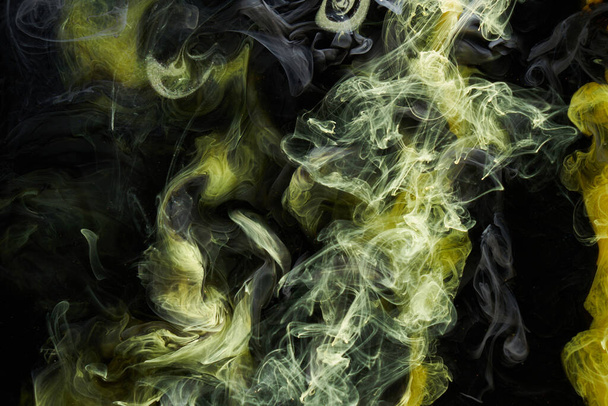 Yellow dark abstract background, luxury colored smoke, acrylic paint underwater explosion, cosmic swirling ink - Фото, изображение