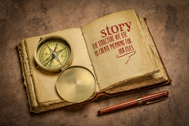 story - the structure we use to create meaning for our lives handwriting in a retro journal with a brass compass, storytelling and interpretation of reality concept - Foto, Imagen