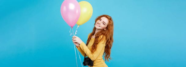 Levensstijl en Party concept - close-up portret jonge mooie aantrekkelijke gember rode haren meisje met kleurrijke ballon en vintage camera. Blauwe Pastel achtergrond. Kopiëren van ruimte - Foto, afbeelding