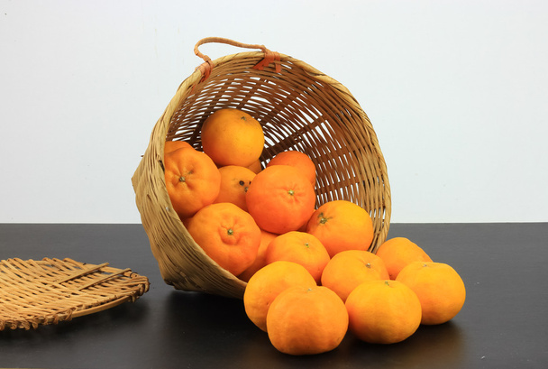 Um monte de laranjas de tangerina em cesta de vime
 - Foto, Imagem
