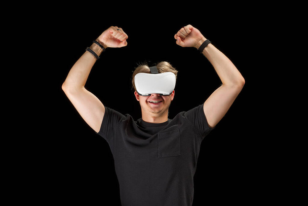 Молодий чоловік, що носить віртуальні окуляри віртуальної реальності, окуляри ізольовані на чорному тлі. У грі на Metaverse та концепції освіти. - Фото, зображення