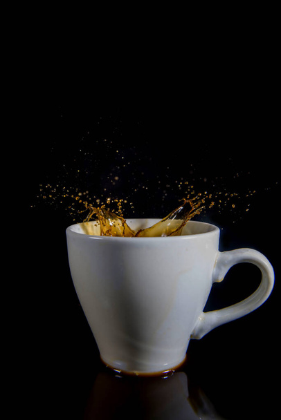 Πιτσιλιές καφέ σε λευκό κύπελλο σε μαύρο φόντο. - Φωτογραφία, εικόνα