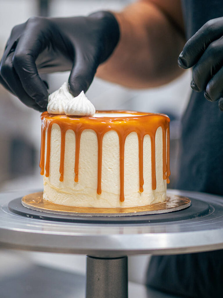 professional baker decorating a chocolate and cream cake with salty caramel - Фото, зображення