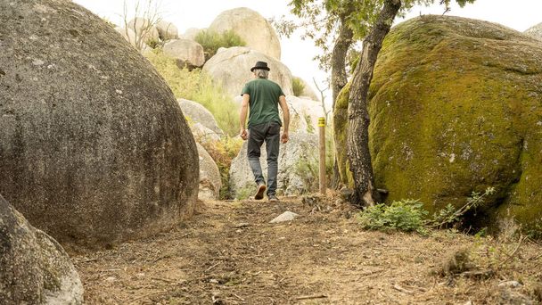 человек пытается окружить камень, окруженный эрозией больших размеров - Фото, изображение