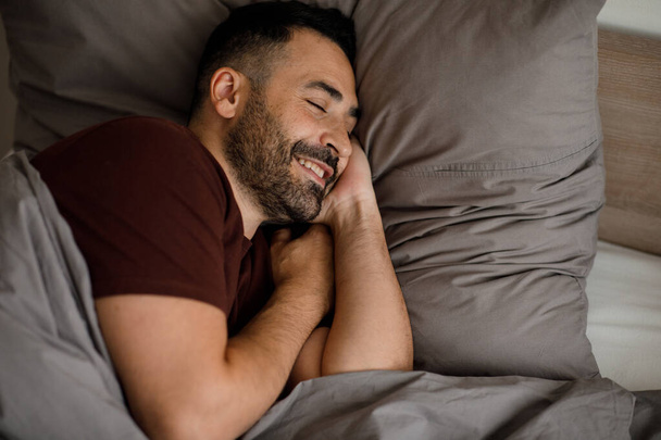 Mutlu adam sabah iyi bir ruh hali içinde gri bir yatakta uyanır. Yüksek kalite fotoğraf - Fotoğraf, Görsel