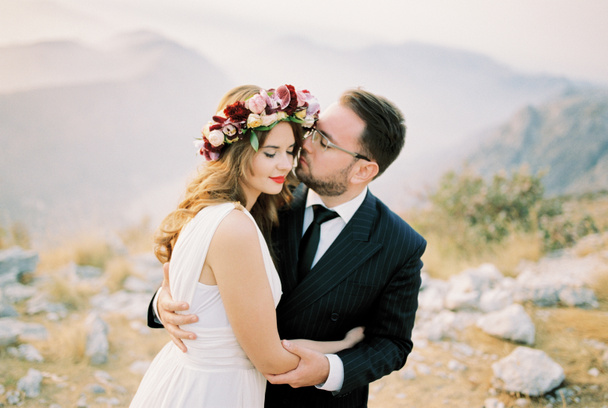 A vőlegény derékon öleli a menyasszonyt, és majdnem arcon csókolja, a hegyen állva. Kiváló minőségű fénykép - Fotó, kép