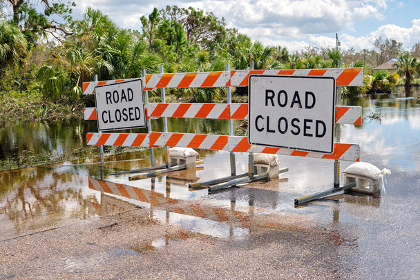 Hurrikan Ian überflutete die Straße mit gesperrten Schildern, die den Autoverkehr blockierten. Transportsicherheit bei Naturkatastrophen. - Foto, Bild