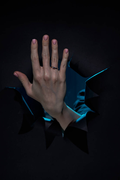 リングの指にダイヤモンドとホワイトゴールドの婚約指輪を示す黒の隔離された背景の上に白人の若い女性の手 - 写真・画像