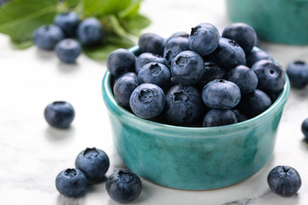 Tasty fresh blueberries on white marble table, closeup - 写真・画像