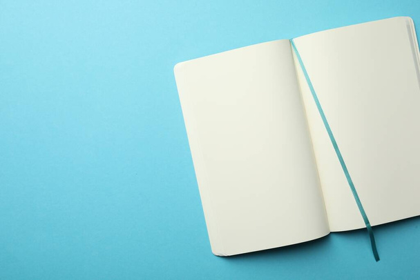Stylish open notebook with blank sheets on light blue background, top view. Space for text - Zdjęcie, obraz