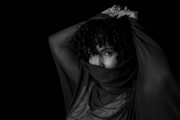 Close-up black and white portrait of woman with transparent cloth on her face against black background. Mature woman. Self-esteem concept. - Fotografie, Obrázek