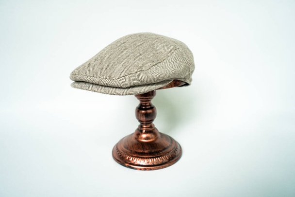 Detail of scally or flat cap in dark brown pattern  herringbone tweed fabric set on a bronze head mannequin on a white background - Photo, image