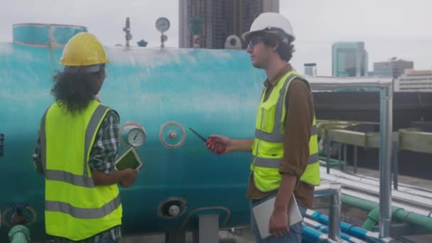 Young woman and man engineer examining pipeline and looking digital tablet in the factory, mechanic or technician inspector plumber valve and talking together, industrial and maintenance concept. - Materiaali, video