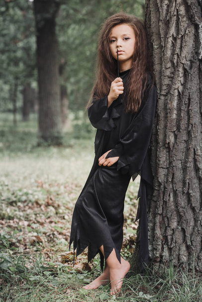 Uma bruxa com uma varinha mágica na floresta. Conceito de Halloween - Foto, Imagem