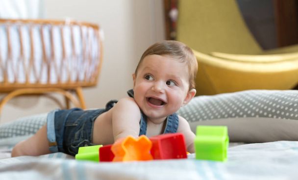 Gelukkig en vrolijk 8 maanden baby spelen thuis met gekleurde bakstenen - Foto, afbeelding